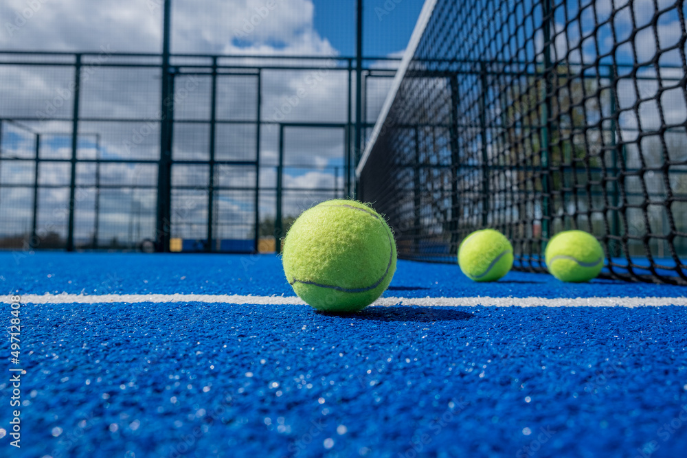 selective focus, four paddle tennis balls on a blue paddle tennis court close to the net