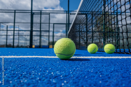 selective focus, four paddle tennis balls on a blue paddle tennis court close to the net © VicVaz
