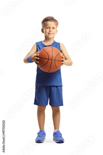 Full length portrait of a boy in a blue jersey holding a basketball and looking at camera