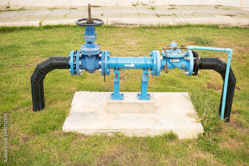 Pumps, valves and Blue steel pipes at park. Self priming sewage pump open bare shaft for repair in garden. photo