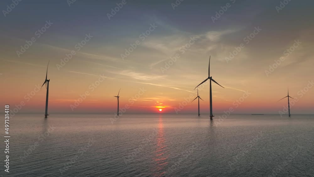 Wind turbines producing sustainable renewable energy in an offshore wind park during sunset. Wind turbines producing sustainable renewable energy in an offshore wind park during sunset.