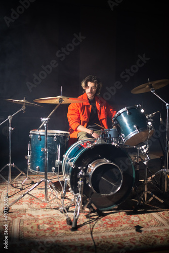 Fotografija Young Caucasian man sitting at drum set in studio