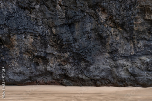 Lava rock wall with sand at base