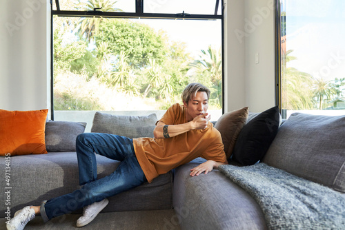Man with hands touching face on sofa by window