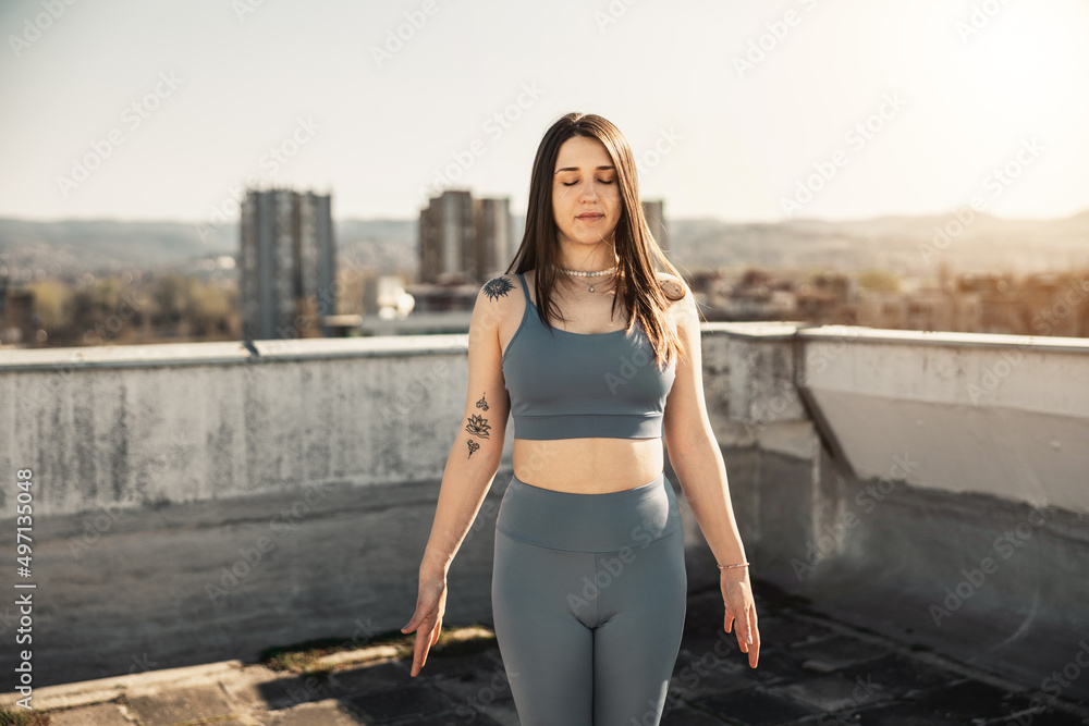 Woman Doing Yoga Outdoors On A Rooftop Terrace At Sunset
