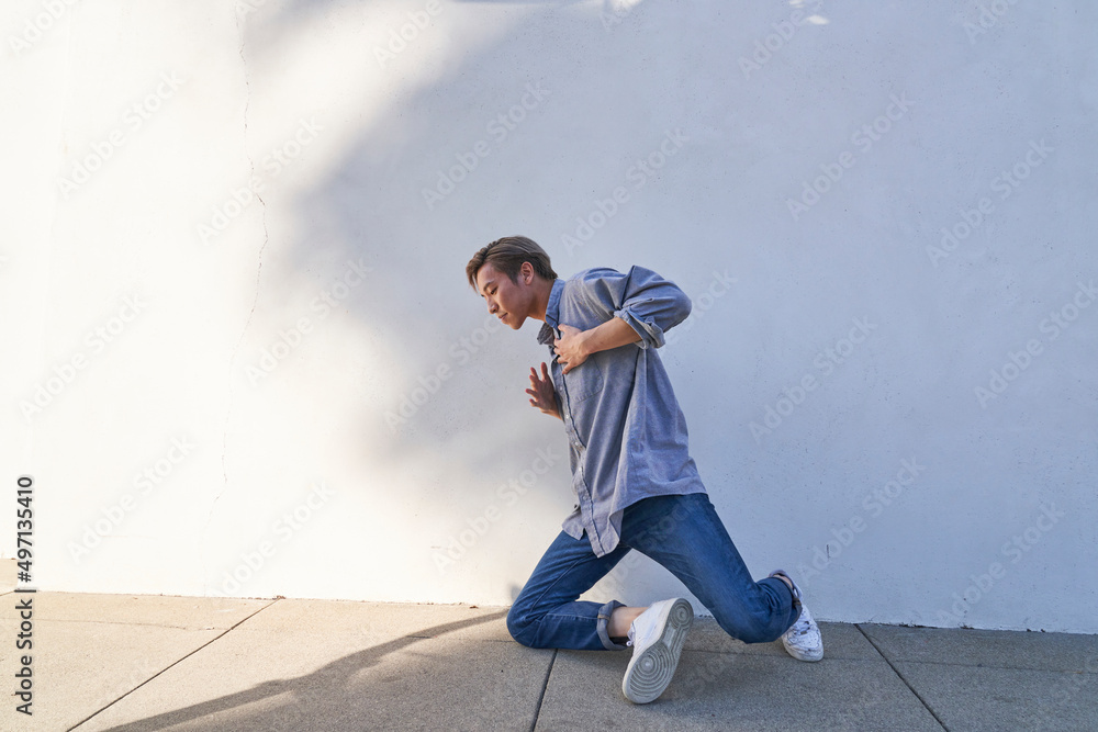 Man dancing touching chest on sidewalk outdoors with plant shadows Man dancing touching chest on sidewalk outdoors with plant shadows