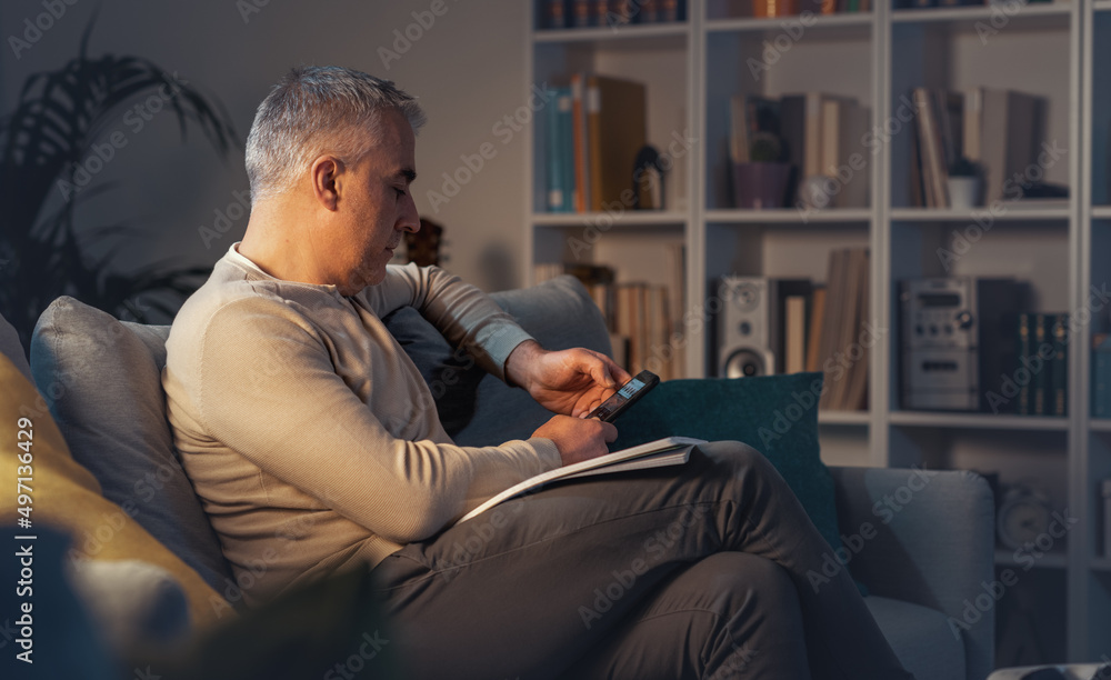 Man relaxing on the couch and connecting with his smartphone