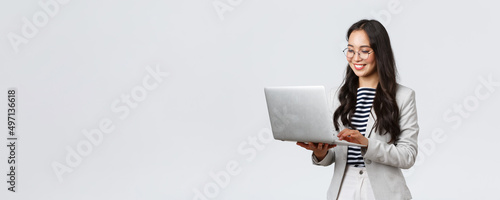 Business, finance and employment, female successful entrepreneurs concept. Professional stylish asian businesswoman fixing project on her way to office, using laptop standing whtie background
