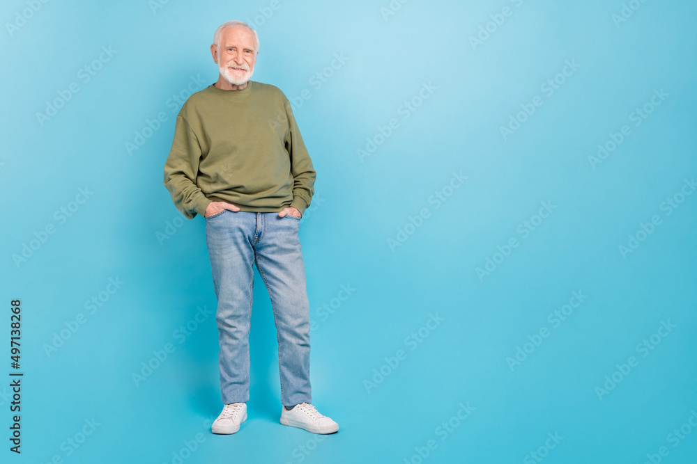 Full length body size view of attractive cheerful grey-haired man holding hands in pockets isolated over vivid blue color background Full length body size view of attractive cheerful grey-haired man holding hands in pockets isolated over vivid blue color background