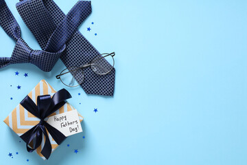 Flat lay composition with Fathers Day gift, necktie, eyeglasses, confetti on pastel blue background.