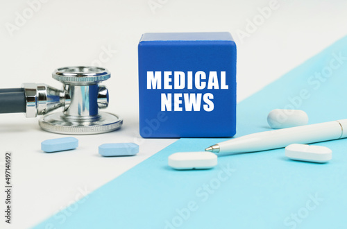 On a white and blue surface are pills, a stethoscope, a pen and a cube with the inscription - MEDICAL NEWS