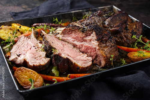 Fototapete Traditional barbecue rack of lamb with carrot and potatoes served as close-up on