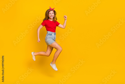 Full body photo of cute teenager girl run wear t-shirt hairband skirt shoes isolated on yellow background