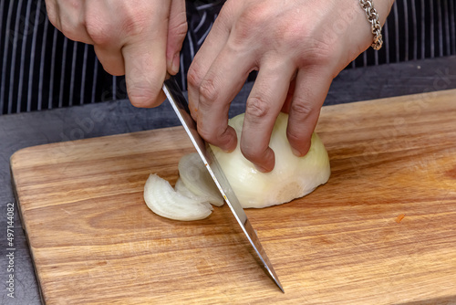 The cook slices the onion into thin slices..