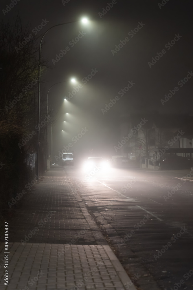 car driving on city road in dark and foggy night