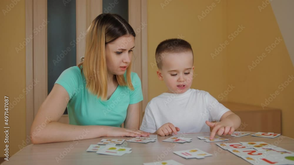Cute pretty child learning and studying with his young mother. Little boy spend time playing educational card game with tutor mom at home. Enjoying maternity, childhood recreation Cute pretty child learning and studying with his young mother. Little boy spend time playing educational card game with tutor mom at home. Enjoying maternity, childhood recreation