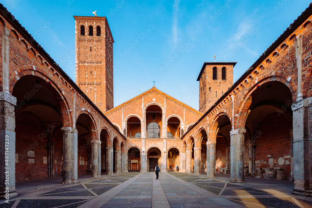 Wide view of the Basilica of Sant'Ambrogio with a tourist in the center of the courtyard
