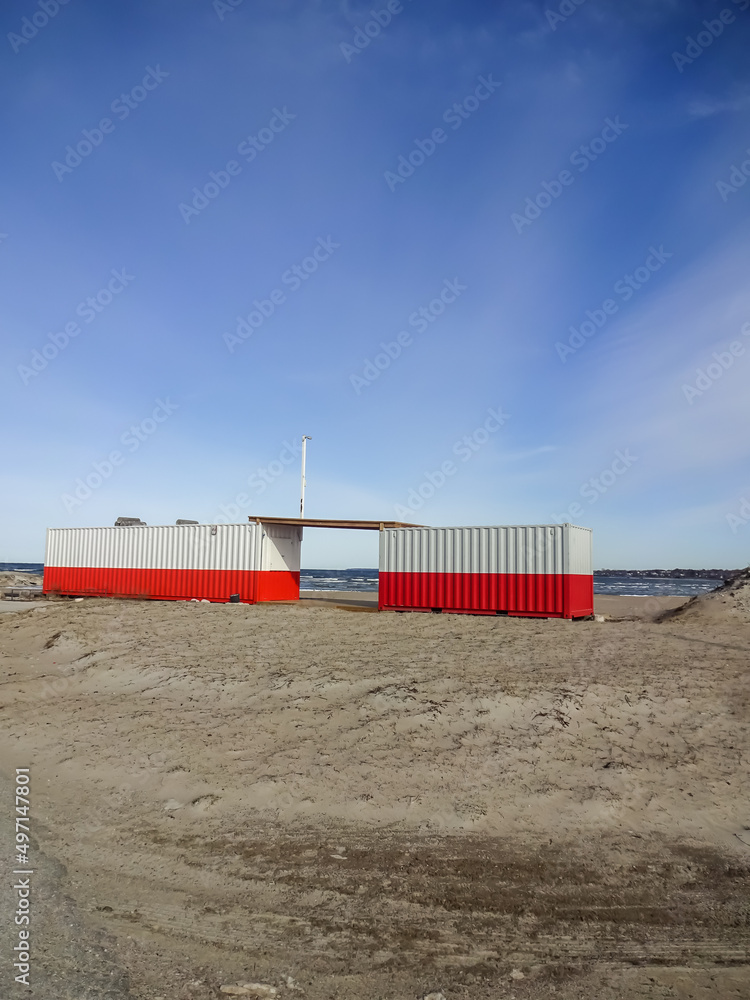 Two red-white containers on empty Pirita sandy beach in Pirita, Tallinn, Estonia, Europe before the season started. Blue sky. March 2022 Two red-white containers on empty Pirita sandy beach in Pirita, Tallinn, Estonia, Europe before the season started. Blue sky. March 2022