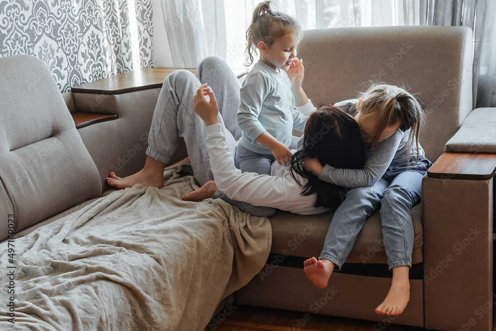 Three sisters of different ages have fun at home on the couch, laugh, hug, express positive emotions and feelings. Three sisters of different ages have fun at home on the couch, laugh, hug, express positive emotions and feelings.