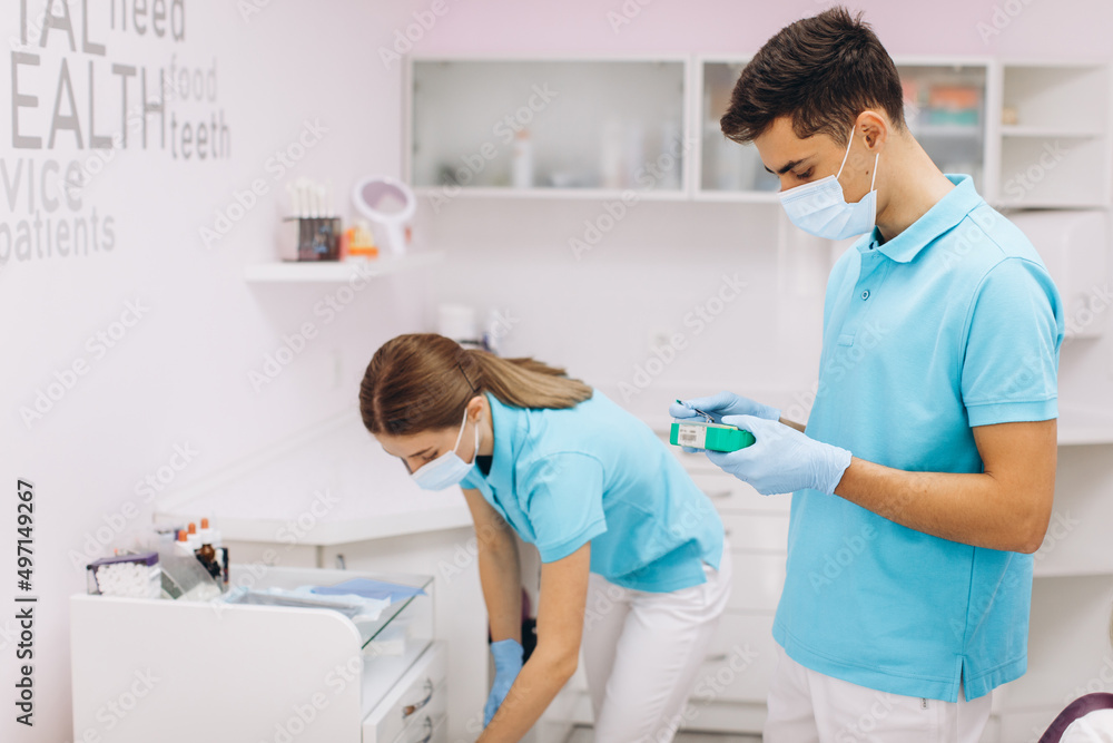 The dentist and his assistant prepare the tool in the dental office The dentist and his assistant prepare the tool in the dental office
