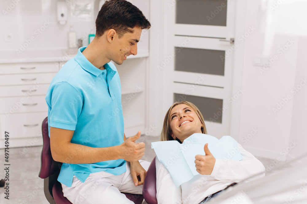 Obraz premium Dentist and woman show each other thumb and smile