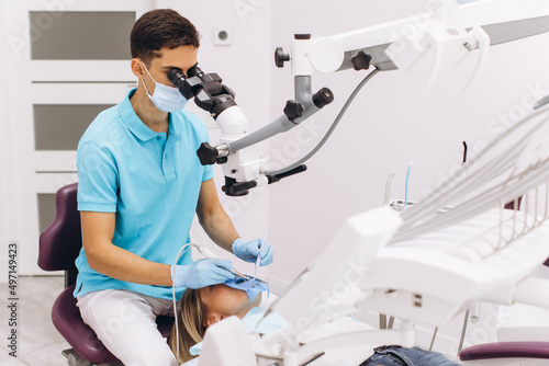 Male dentist examining woman looking on the teeth with professional microscope in the surgery dental office