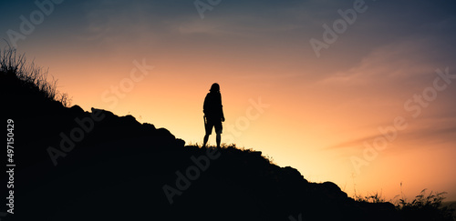 silhouette of man standing on top of mountain watching the sunset