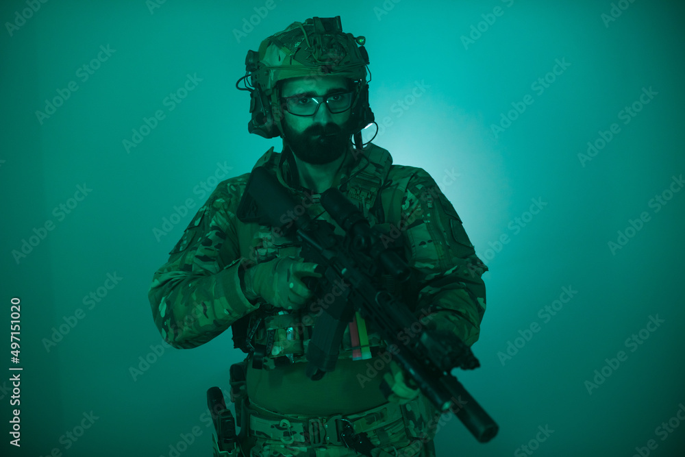 Fototapeta premium Portrait of man in military uniform. Bearded man in army ammunition holding machine gun. Portrait, army, weapon airsoft concept