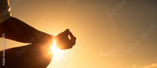Fotografiet Hand meditating against sunset sky background