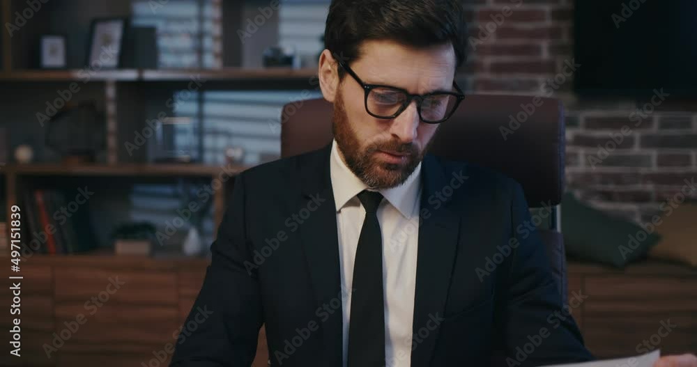 The trader checks the exchange rates. Man portrait in cinematographic light. Handsome businessman is working in the office. The trader checks the exchange rates. Man portrait in cinematographic light. Handsome businessman is working in the office.