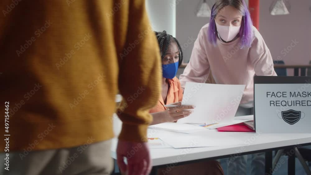 The young professor is checking the homework of her student and a medical worker is measuring the temperature The young professor is checking the homework of her student and a medical worker is measuring the temperature