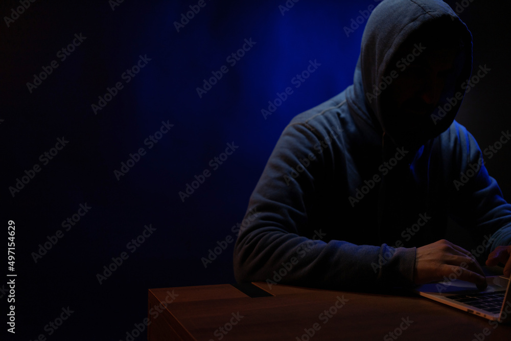 Hacker man working laptop computer. Hacker attack in dark room Hacker man working laptop computer. Hacker attack in dark room