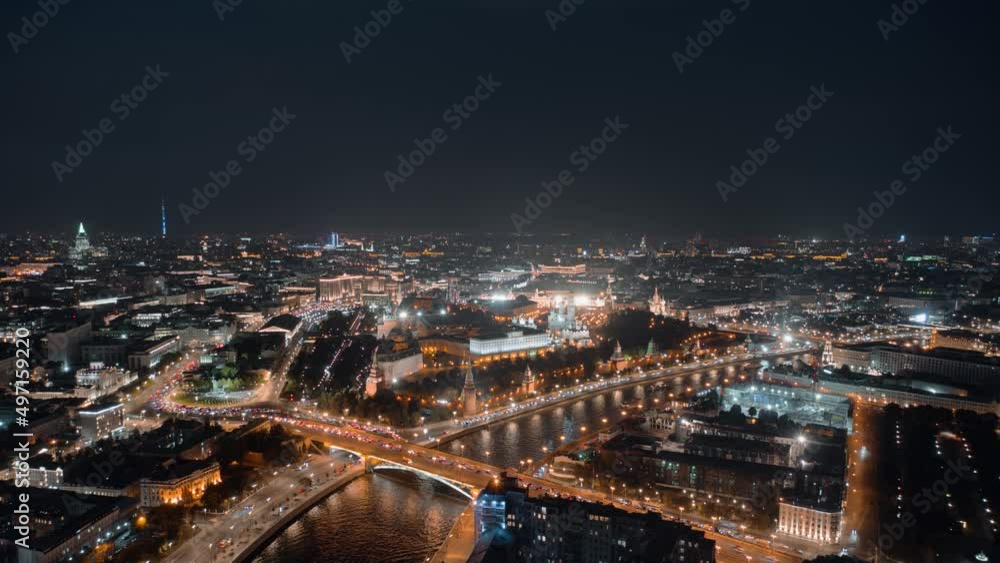 Beautiful aerial panorama of Moscow Kremlin at night. View from above to the towers of Kremlin, Moskva River and Kremlevskaya Naberezhnaya with evening lights and busy traffic in motion timelapse.
