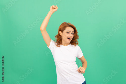 happy redhead woman with curly hair dancing having fun on blue background, have fun