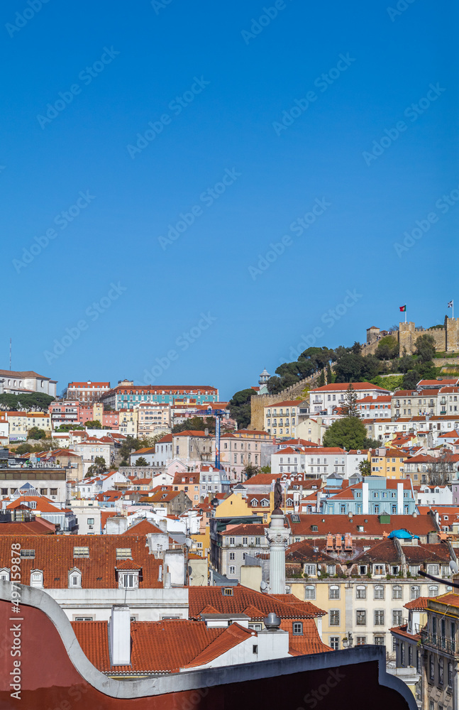 Colorful building facades in downtown Lisbon fill the urban environment with historic and traditional architecture. São Jorge Castle in the background. Image with selective focus.