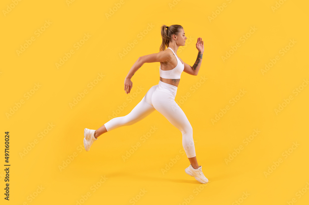 energetic sport woman runner running on yellow background