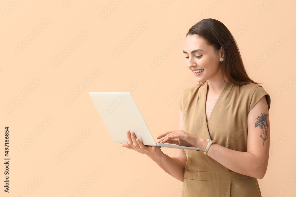 Pretty young businesswoman using laptop on beige background Pretty young businesswoman using laptop on beige background