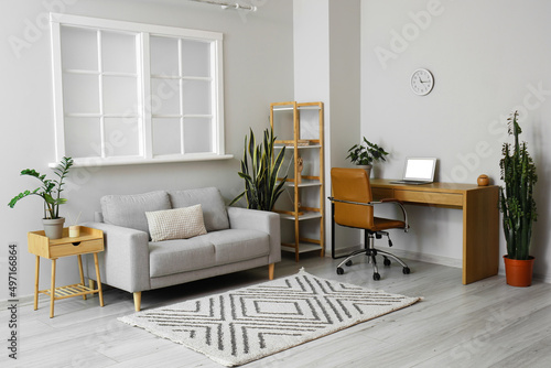 Fototapeta Naklejka Na Ścianę i Meble -  Interior of light living room with grey sofa and modern workplace