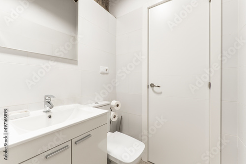 Bathroom with white furniture  white resin sink  frameless mirror and white tiles