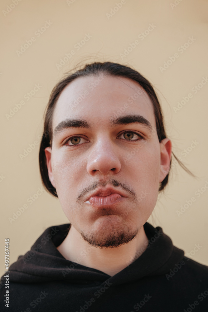 Obraz premium young Caucasian guy bites sour unripe citrus. A man makes a face because of the sour taste of fruit, posing on a green background. Vitamin C.