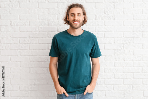Handsome young man in t-shirt on white brick background