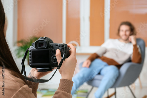 Female photographer taking picture of handsome man in studio, closeup