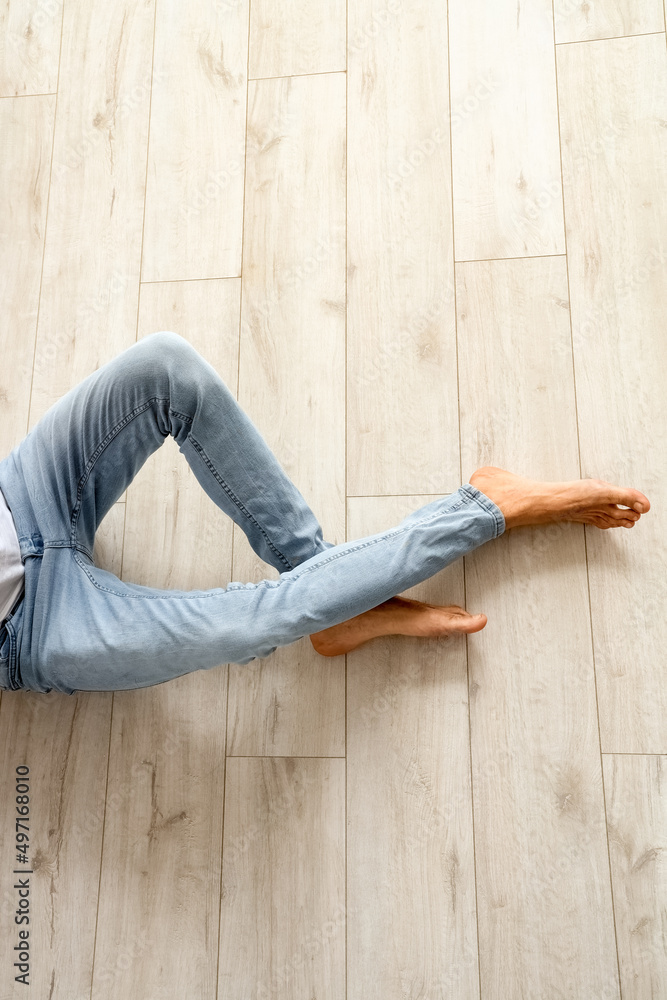 Young barefooted man sitting on wooden floor Young barefooted man sitting on wooden floor