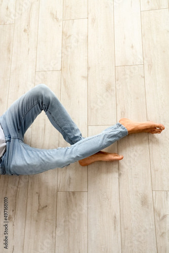 Young barefooted man sitting on wooden floor
