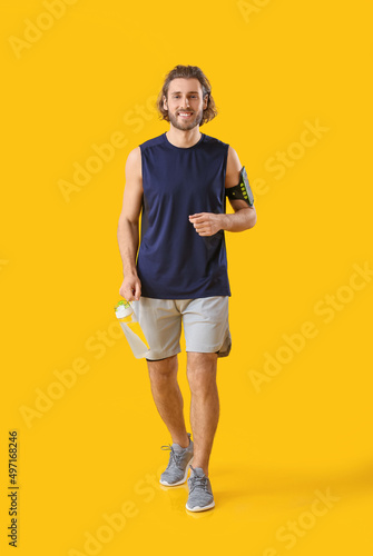 Sporty man with bottle of water on orange background © Pixel-Shot