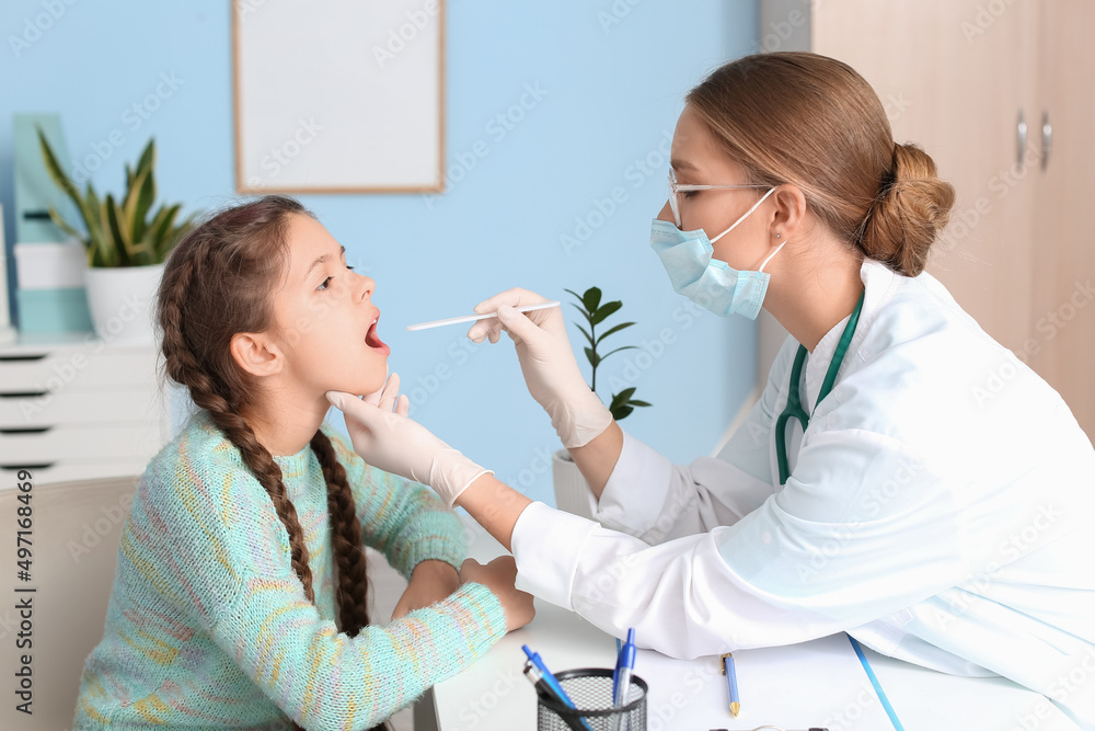 Doctor examining little girl's throat in clinic Doctor examining little girl's throat in clinic