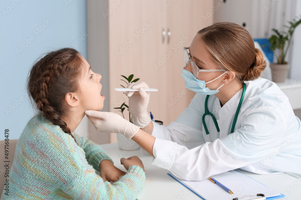 Doctor examining little girl's throat in clinic Doctor examining little girl's throat in clinic