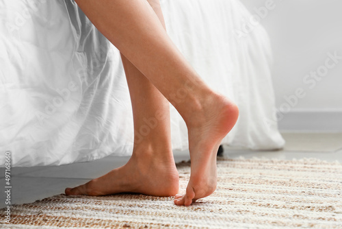 Female bare feet near bed at home, closeup