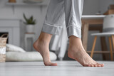 Barefoot woman in pajamas at home, closeup