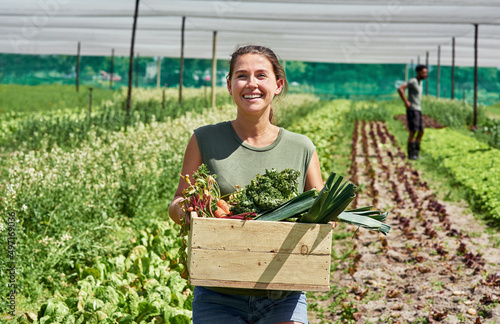 Fresh produce coming right up. Portrait of an attractive young woman carrying a crate full of vegetables outdoors on a farm. photo